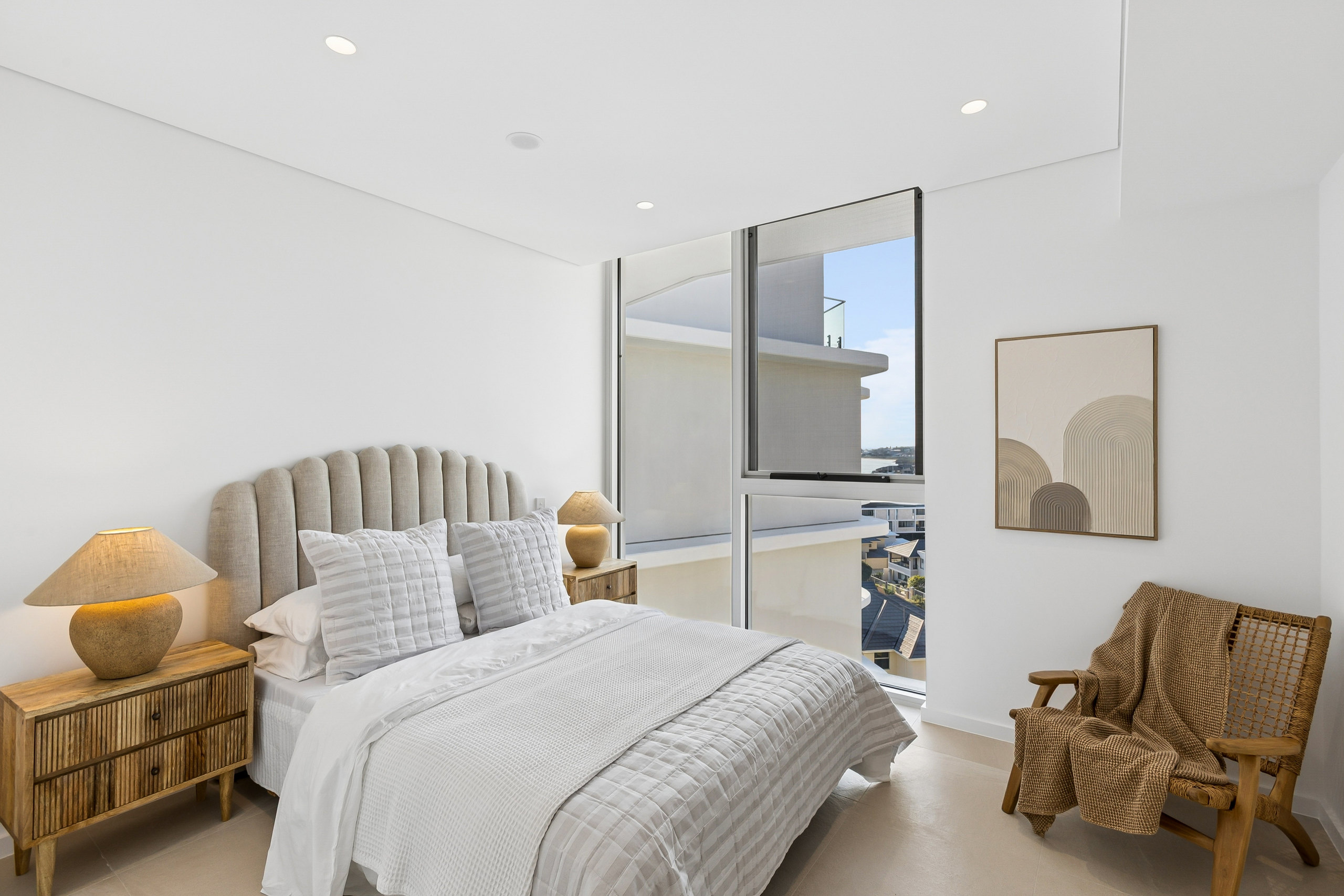 Bedroom with a fluted linen bedhead, rattan lamps and a marina outlook